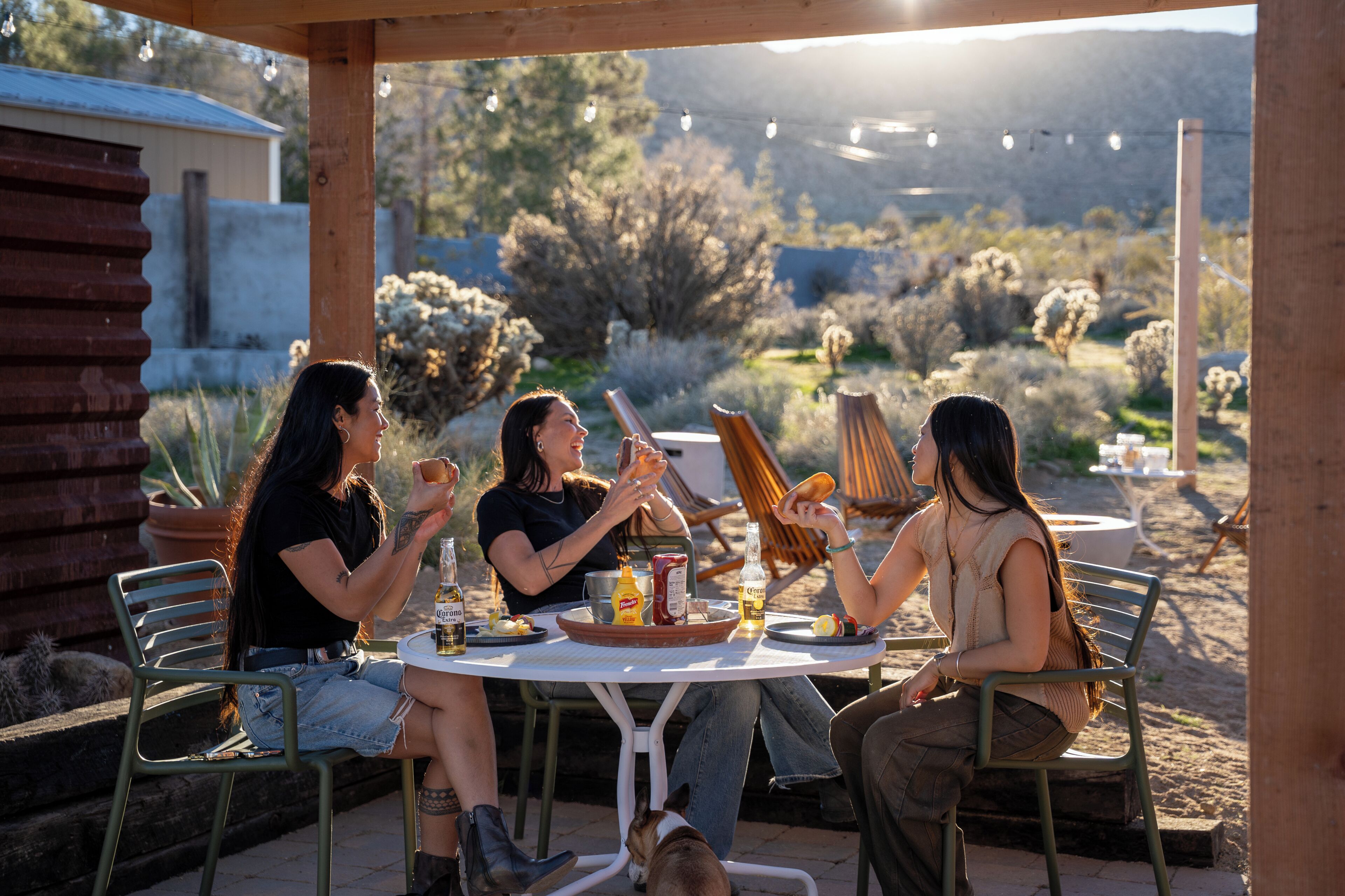 An outdoor dining area with a round table, chairs, and a wooden pergola.