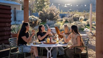 An outdoor dining area with a round table, chairs, and a wooden pergola.