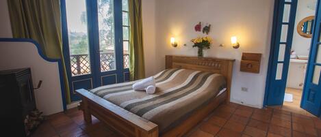 Un dormitorio con cama de madera, chimenea y vistas al exterior a través de una puerta azul.