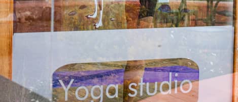 Un studio de yoga doté d’un mur de verre qui reflète une personne effectuant une posture de yoga.