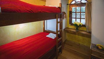 Habitación con literas, una escalera de madera, una ventana con vistas y una mesita con un florero.