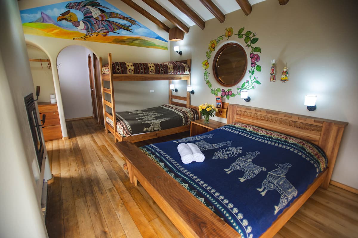 Una habitación con literas, piso de madera, un mural en el techo y luces fijadas a la pared.