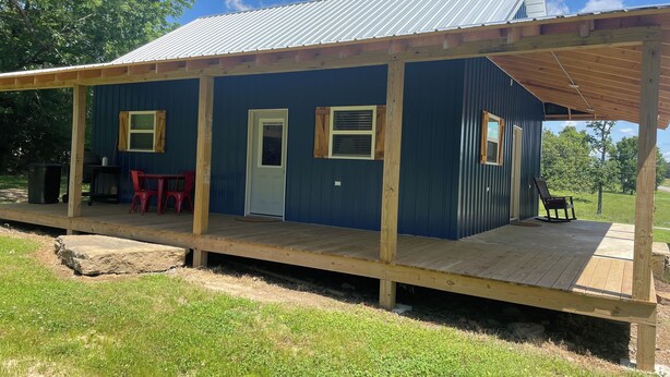 Una baita blu con veranda in legno, una porta e due finestre.