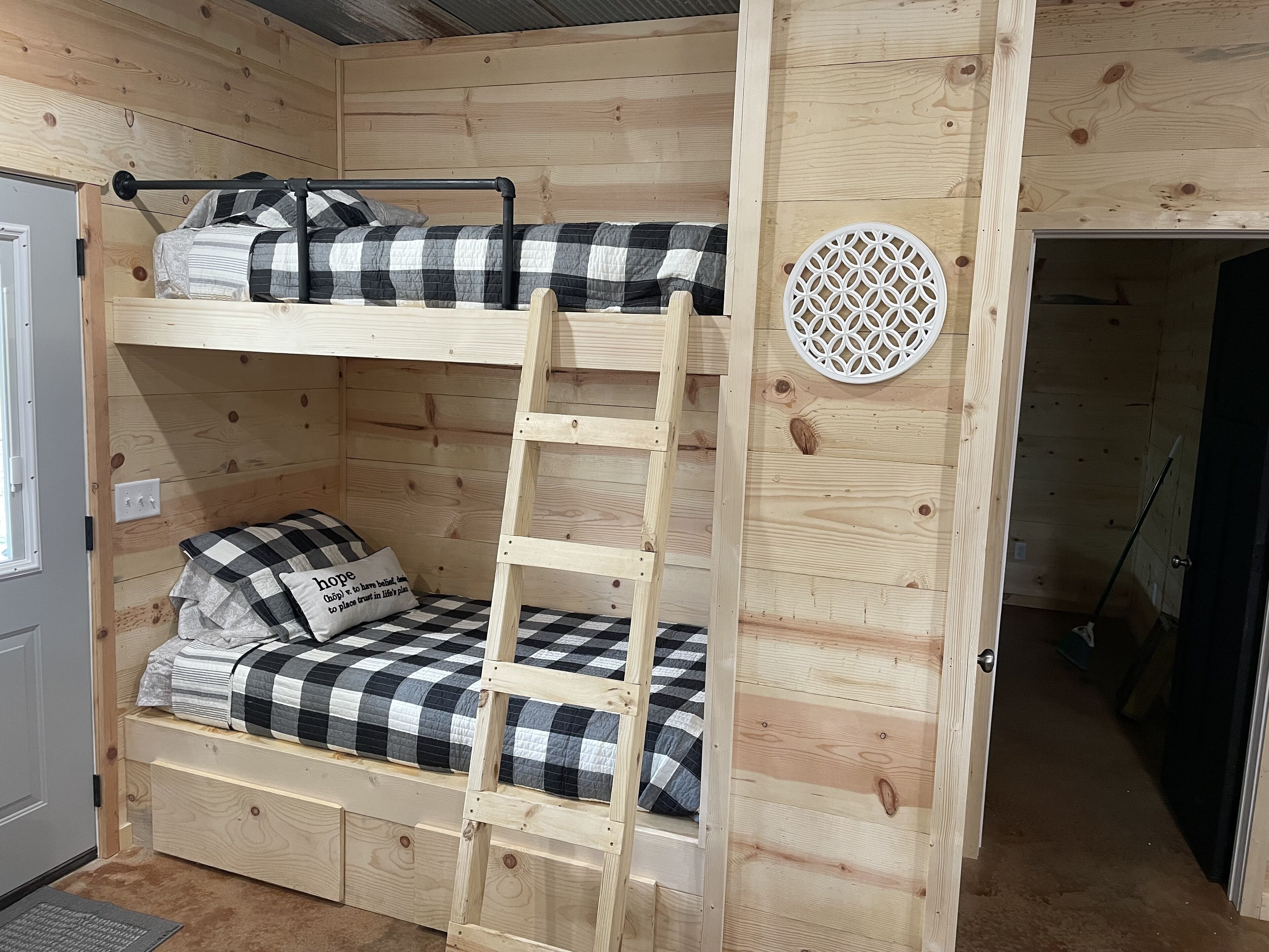 A bunk bed with a ladder, checkered bedding, and a decorative wall piece.