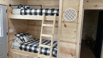 A bunk bed with a ladder, checkered bedding, and a decorative wall piece.