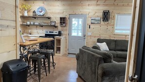 Un accogliente interno di una baita con angolo cottura, zona pranzo e salotto.