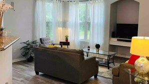 Ein modernes Wohnzimmer mit einer Couch, einem Glastisch und einem Fernseher.