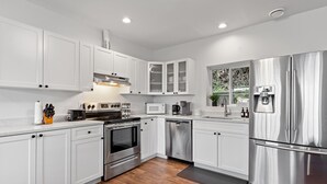 A modern kitchen with white cabinets, stainless steel appliances, and a built-in microwave. - Private Mountainside Home - close to hiking trails and rivers. (Chilliwack)