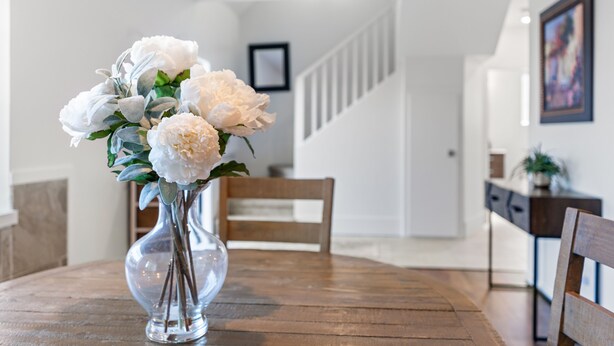 A wooden dining table with a clear glass vase containing white flowers. - Private Mountainside Home - close to hiking trails and rivers. (Chilliwack)