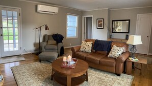 A living room with a brown leather sofa, a round coffee table, a grey armchair, and a patterned rug. - Cozy 2 br. Close to River (Milwaukie)