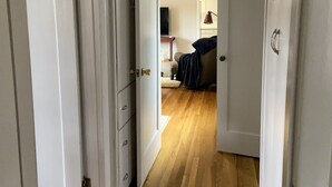 A hallway with wooden flooring leading to a bedroom with a bed and a nightstand. - Cozy 2 br. Close to River (Milwaukie)