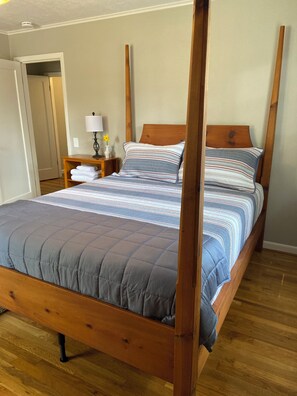A four-poster bed with a wooden frame, a grey quilted duvet, and striped pillows. - Cozy 2 br. Close to River (Milwaukie)