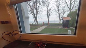 A kitchen with a window overlooking a yard with trees and a fence. - Holiday home right on the bank with a view (Balatonboglár)