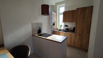 Una cocina compacta con una isla central, armarios de madera y una lámpara colgante.