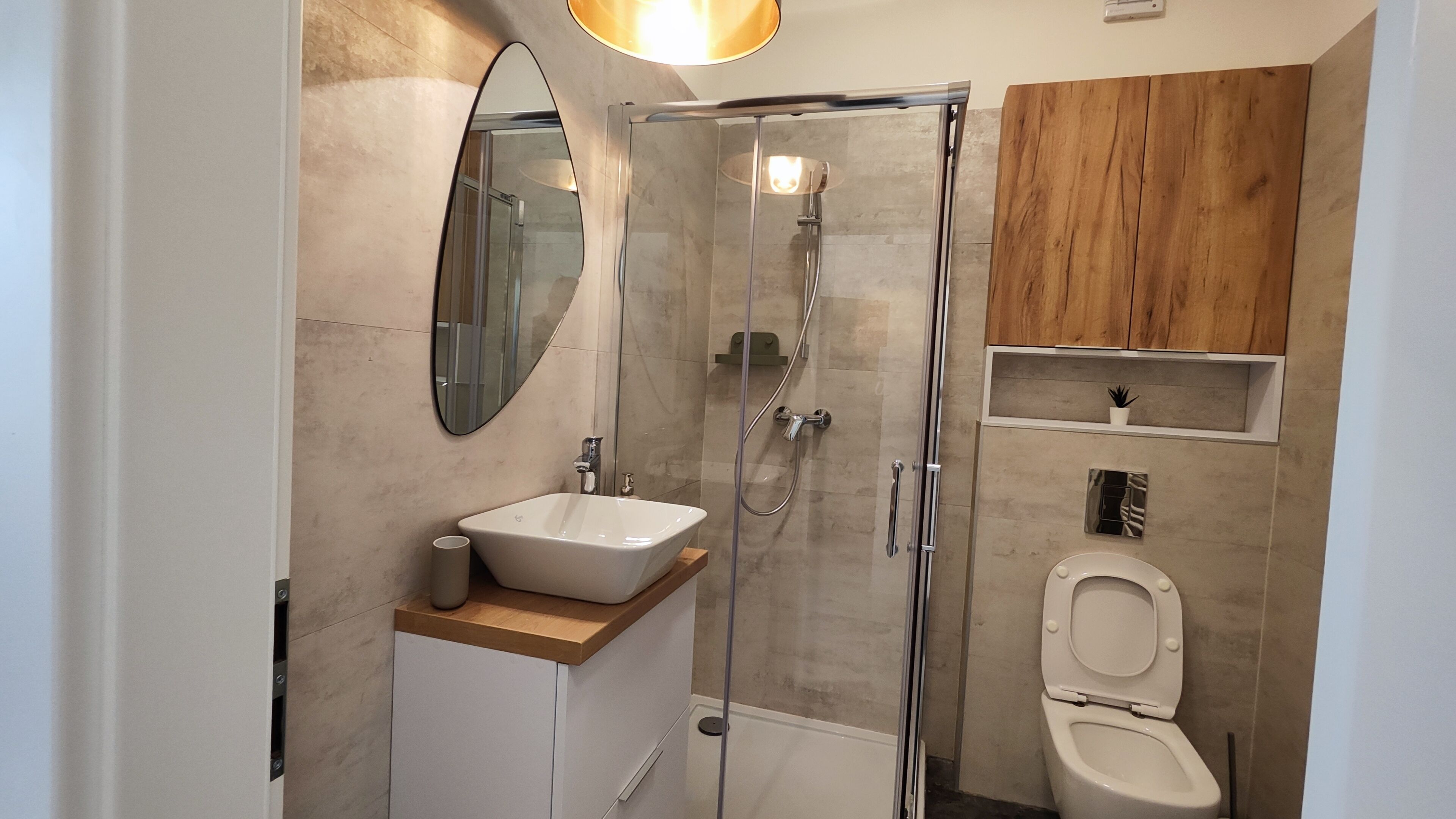A modern bathroom with a glass-enclosed shower, a white sink, and a toilet.
