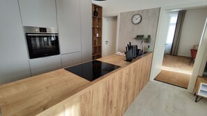 A modern kitchen with a built-in oven, wooden countertop, and a clock on the wall. - DOHNANYI Villa by CHORS (Trencin)