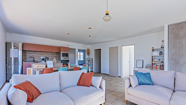 A modern living room with two sofas, a coffee table, and a kitchen in the background.