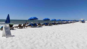 A beach with rows of blue umbrellas and lounge chairs.