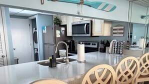 A modern kitchen with a large island, stainless steel appliances, and wooden chairs.