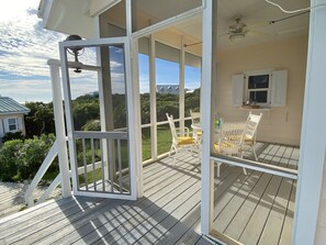 Une terrasse extérieure couverte, dotée de rampes blanches et de meubles en osier.