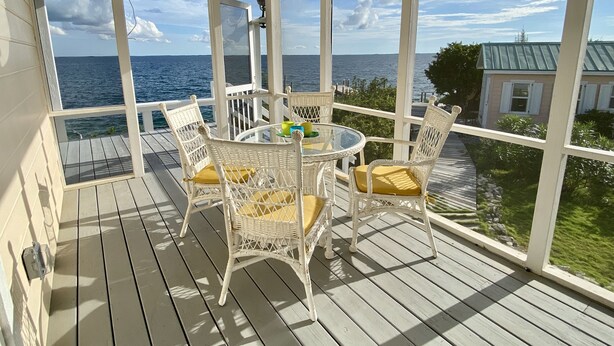 A covered outdoor area with a table and chairs, overlooking the sea. - Private Oceanfront Home on the Bay of Great Guana Cay - Spectacular Views! (Great Guana Cay)