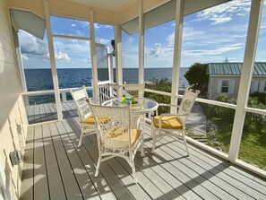Un espace extérieur abrité, doté d’une table et de chaises, avec vue sur la mer.
