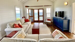 A spacious living room with a high ceiling, a large window, and a view of the sea. - Private Oceanfront Home on the Bay of Great Guana Cay - Spectacular Views! (Great Guana Cay)
