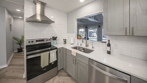 Una cocina moderna con azulejos blancos, electrodomésticos de acero inoxidable y una ventana con vistas.