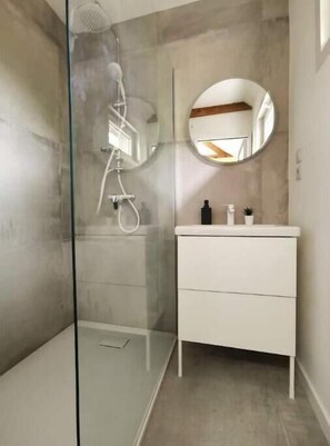 Bathroom features a glass-enclosed shower and a wall-mounted control panel.