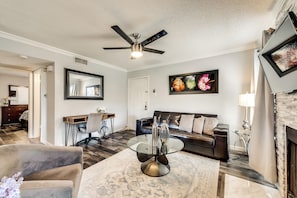 A living room with a ceiling fan, a sofa, a coffee table, and a fireplace.
