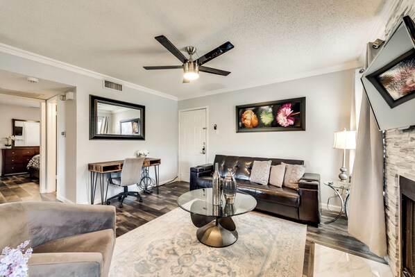 A living room with a ceiling fan, a sofa, a coffee table, and a fireplace.