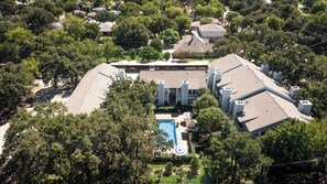 A residential building with a swimming pool, surrounded by trees.