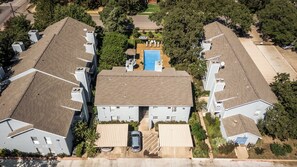 A residential building with a central swimming pool, multiple balconies, and a parking area. - I00 - Gated Irving 2BR | DFW 10Min | Patio + Pool (Irving)