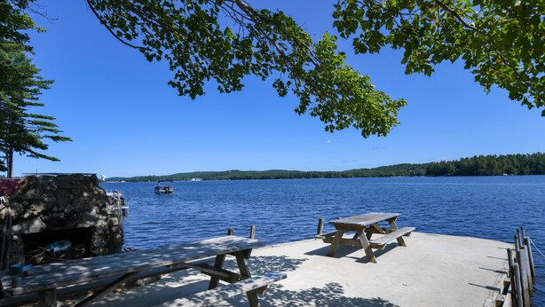 A lakeside picnic area with benches and a stone structure. - Quiet Brandy Pond Retreat with Sunset Views & Water Access (Naples)