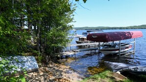 A lakeside dock with boats and a covered area. - Quiet Brandy Pond Retreat with Sunset Views & Water Access (Naples)