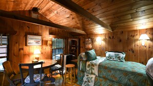 A wooden cabin with a bed, a dining table, and a chair. - Quiet Brandy Pond Retreat with Sunset Views & Water Access (Naples)