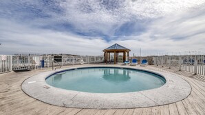 A pool area with a gazebo, wooden deck, and lounge chairs. - Sugar Beach Condominiums (Orange Beach)