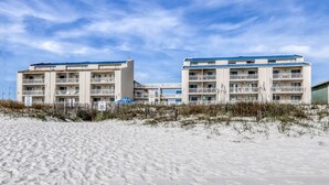 A beachfront hotel with multiple balconies and a sandy beach in the foreground. - Sugar Beach Condominiums (Orange Beach)