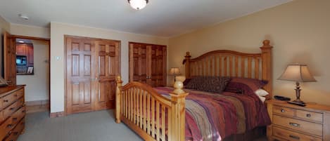 A bedroom with a wooden bed, a nightstand, a dresser, and a closet.