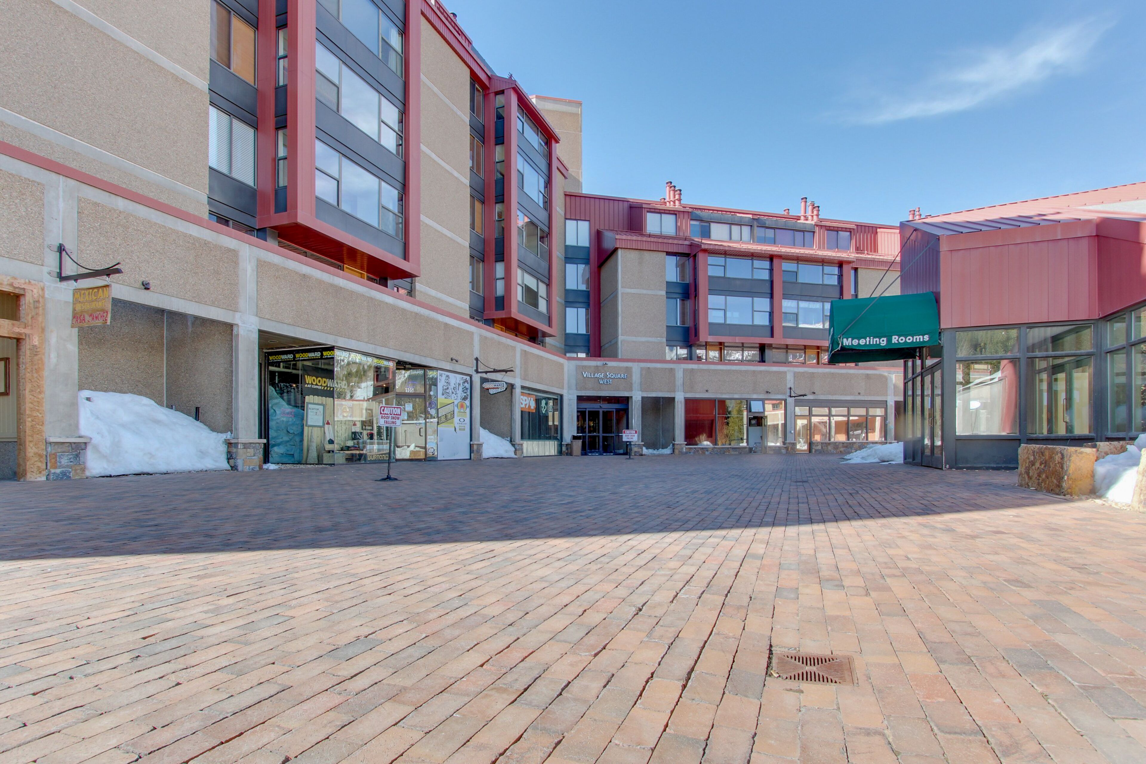 Una plaza con adoquines y un edificio moderno que muestra un cartel que dice 'Meeting Rooms'.
