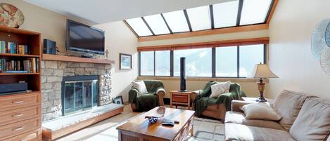 A living room with a fireplace, a television, and a large window.