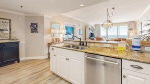 A modern kitchen with white cabinetry, granite countertops, stainless steel appliances, and a large window offering a view. - Sterling Shores (Destin)