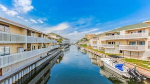 A canal view with waterfront buildings, a boat docked on the right, and a clear sky. - Sandpiper Cove (Destin)