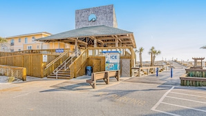 A beachside building with a wooden structure, a staircase, and a sign for 'Ice' vending. - Sandpiper Cove (Destin)