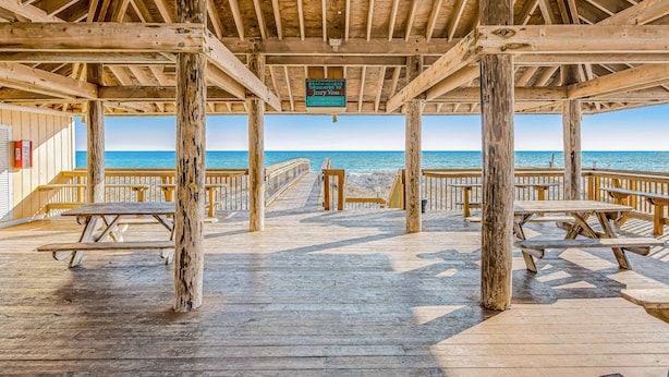 A wooden pier with picnic tables and a sign dedicated to Jerry Voss. - Sandpiper Cove (Destin)