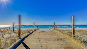 A wooden boardwalk leading to a beach with a clear blue sky. - Sandpiper Cove (Destin)