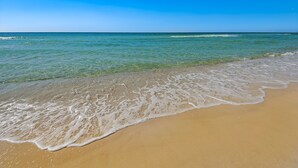 Una playa con agua azul cristalina y una orilla arenosa.