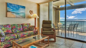 A room with a sofa, a chair, a glass table, and a view of the ocean through a sliding glass door. - Kona Bali Kai (Kailua-Kona)