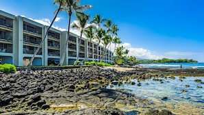 A hotel with multiple floors, a rocky shoreline, and palm trees. - Kona Bali Kai (Kailua-Kona)