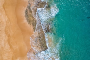 An aerial view of a beach with clear turquoise waters and a sandy shoreline. - Vacasa at Hotel Molokai (Kaunakakai)